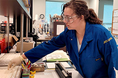 Lab person reaching over materials to access items needed